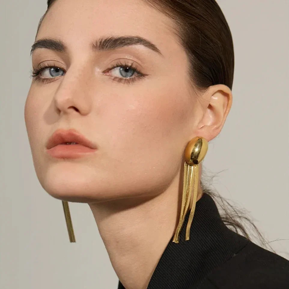 Woman wearing oversized gold statement earrings with fringe chains