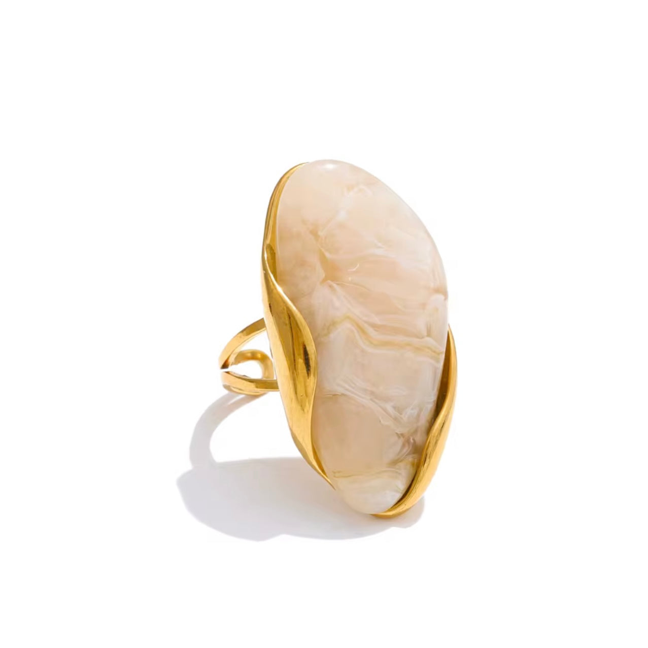 Gold ring with large oval white gemstone on a white background